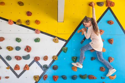 Young girl climbing on "climbing wall" structure.