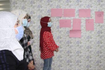 A group of young people stand next to their artwork.