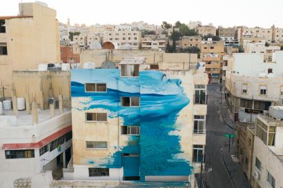 A scene of amman, jordan focused on a building with a large mural of a woman with hair blowing in the wind.