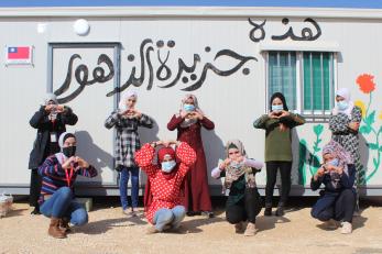 A group of young people pose together outside a temporary structure they designed and decorated themselves.