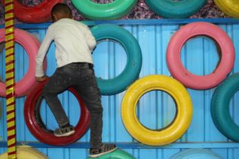 A young person climbing a wall of tires.