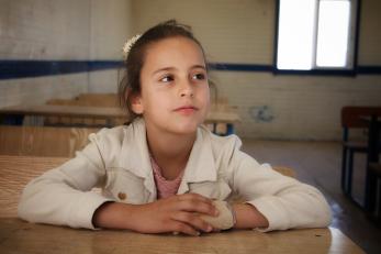 A young person sitting at a table and listening attentively.