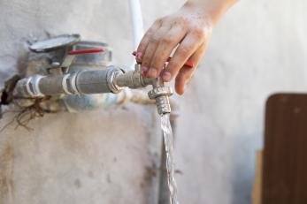 Hand turning on water spigot.