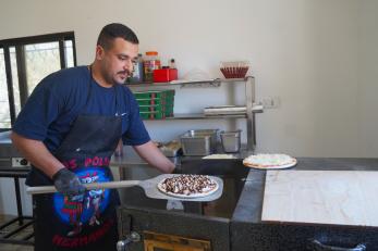 Montaser in action making his signature pizza in his home kitchen.