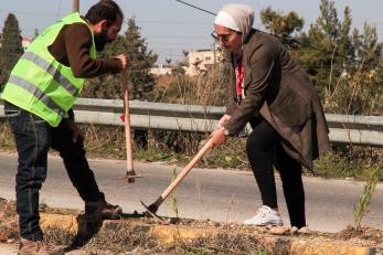 A community member and mercy corps employee work together to plant a tree.