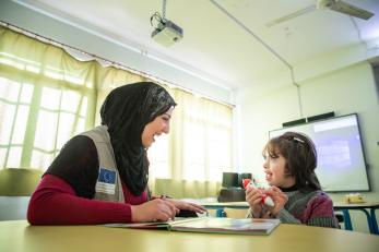 Mercy corps employee and student work together in a classroom.