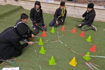 Young people site in a group and interact with a team building exercise.