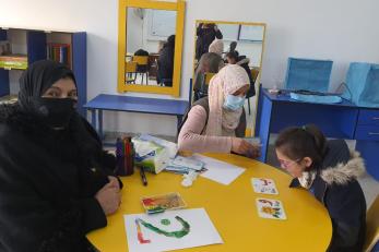 A student learning at a table with their teacher and parent.