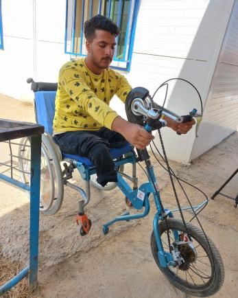 A person testing the fit on a customized wheelchair. 