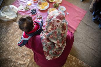 Mother and child on rug on floor with food.
