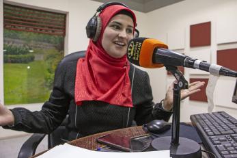 A person wearing headphones speaks into a microphone inside a broadcast studio in Jordan. 