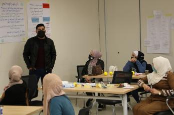 Man speaks in front of community in classroom setting.