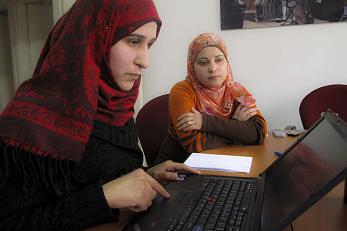 An adult and child focus on a laptop.