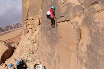 A young person climbs a rock wall. 