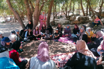 A group of young people sitting together among trees.