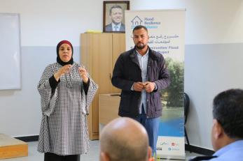 Two people leading a presentation to a group of adults.