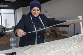 A person laying materials on a table to produce reusable totes. Photo courtesy of Cathy Cheney