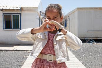 A young person making a heart shape with their hands.