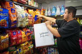 Man stocking shelves of his convenience store in Jordan.