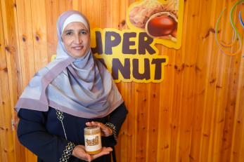Entrepreneur stands in front of her logo with a sample of her product.