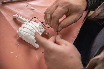 Tamer, a volunteer at Mercy Corps’ disability equipment repair workshop, assembles the pieces of Mohammad’s new 3D printed prosthetic hand.