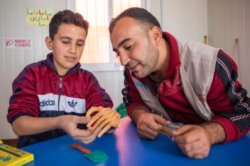 Mohammad works with Saleh, a Mercy Corps trained teaching assistant, to learn how to strengthen his muscles and use his new prosthetic hand.
