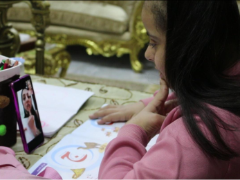 A jordanian girl interacts with her teacher on a phone video chat.