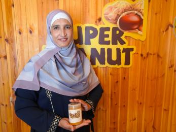 Entrepreneur stands in front of her logo with a sample of her product.