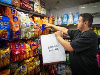 Man stocking shelves of his convenience store in Jordan.
